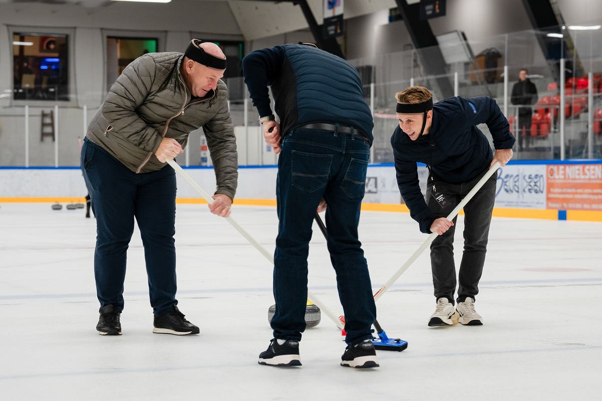 Medlemmer fejer foran en curlingsten