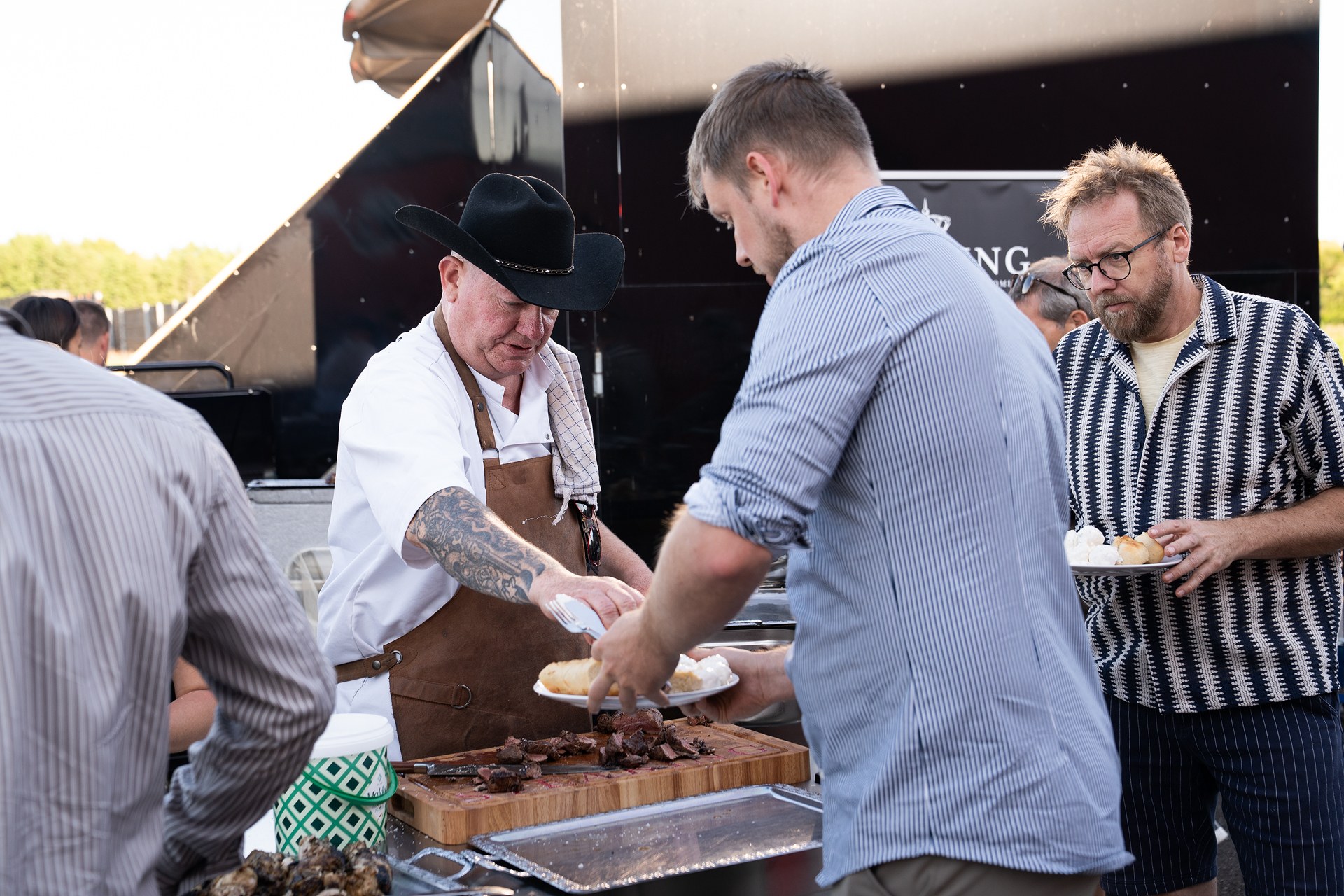 En kok i cowboyhat serverer grillkød for gæsterne